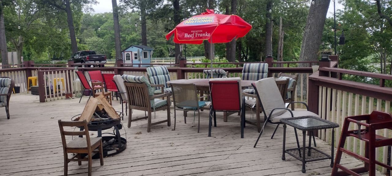 Pemberton Coffeehouse deck — wrought-iron fire pit and a patio table under a red umbrella, stacked logs ready to burn
