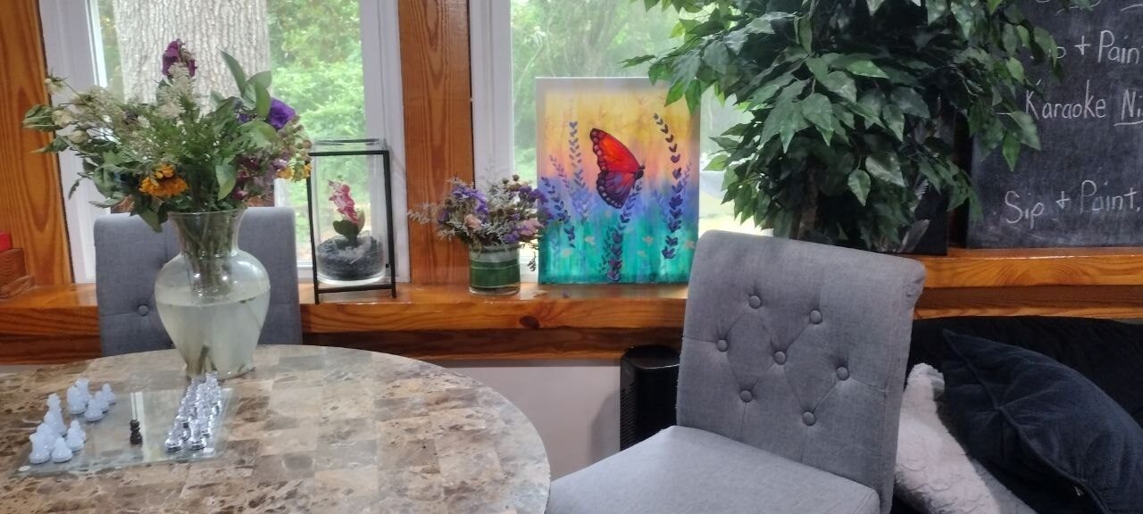 Pemberton Coffeehouse marble café table — a fresh wildflower bouquet and a glass chess set in play by the window