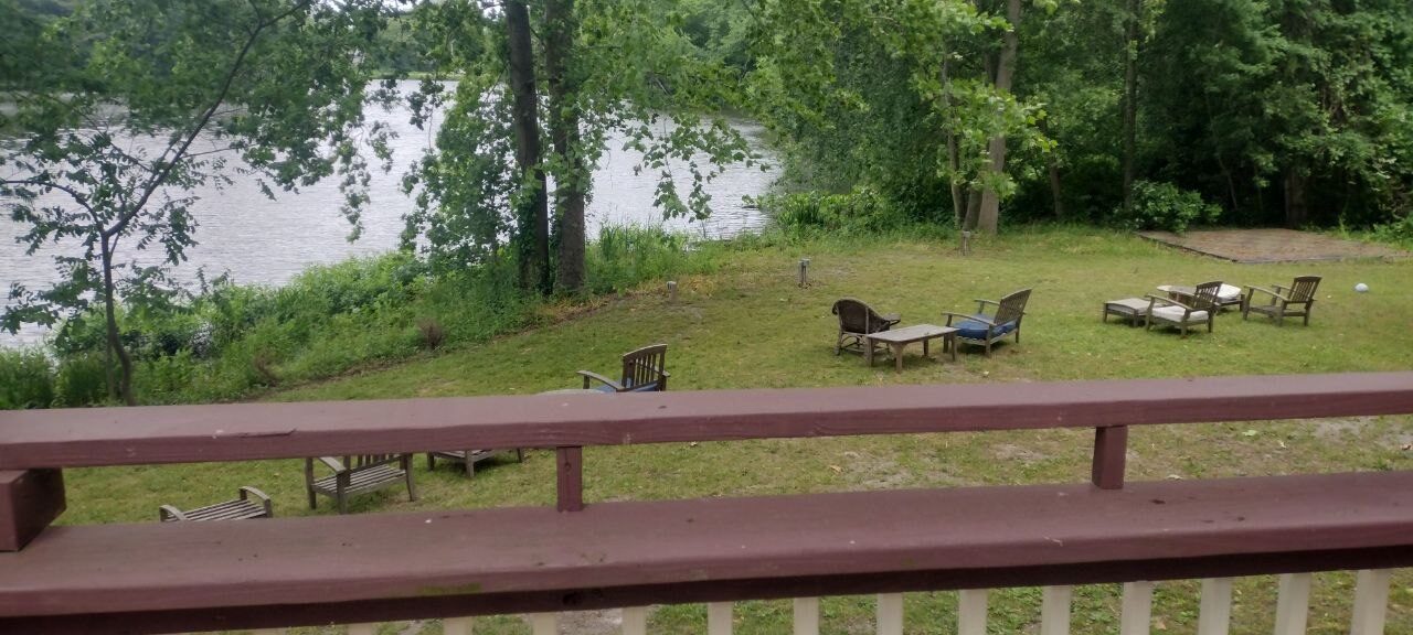 Pond view from Pemberton Coffeehouse upper deck — Adirondack chairs on a sloped lawn descending to the water